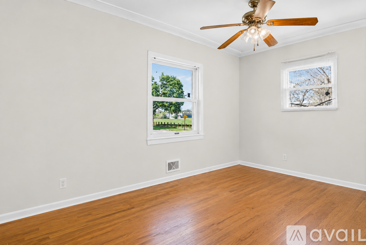 A room with a ceiling fan and two windows.