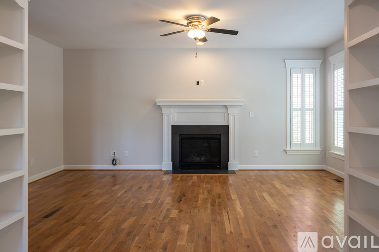 A living room with a fireplace and a ceiling fan.