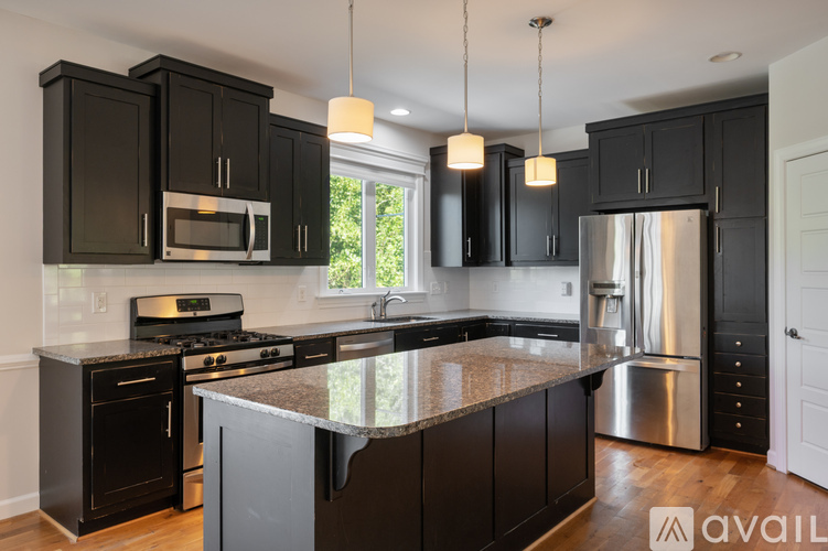 A kitchen with black cabinets and a granite countertop.