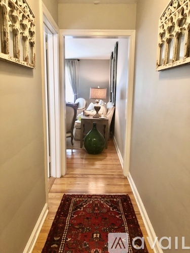 A hallway with a rug on the floor and a mirror on the wall.