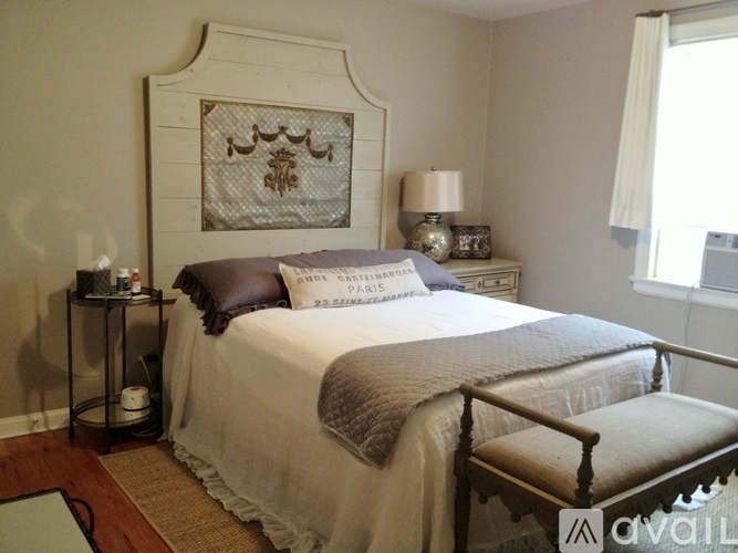A bedroom with a bed, nightstand, and a wall hanging.