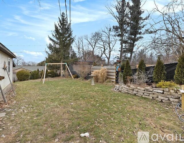 A backyard with a wooden fence and a small tree.