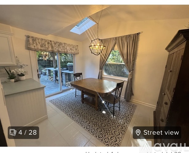 A dining room with a table and chairs, a chandelier, and a skylight.