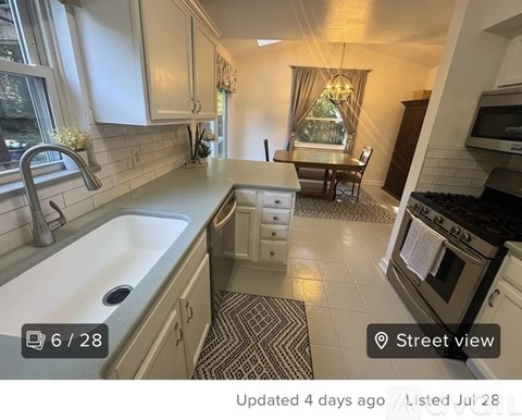 A kitchen with a white sink and a black and white tiled floor.