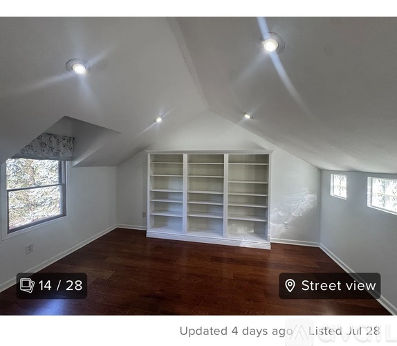 A room with a window and a shelf in the corner.