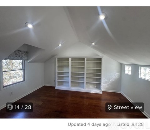 A room with a window and a shelf in the corner.