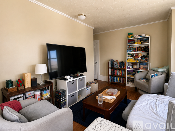 A living room with a grey couch, a coffee table, a television, and a bookshelf.