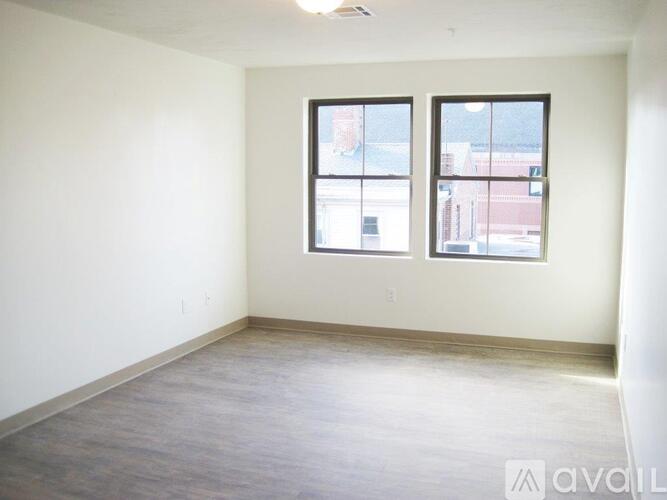 A spacious room with two windows and a view of a building outside.