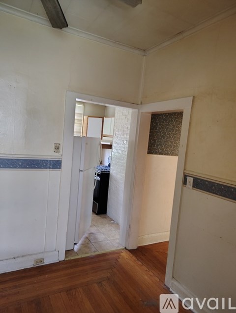A room with a white wall and a doorway leading to another room.