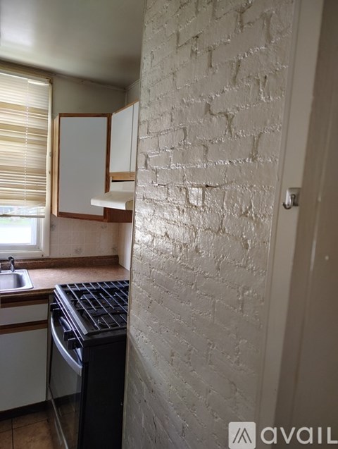 A kitchen with a black dishwasher and a white brick wall.