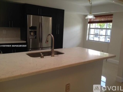 A kitchen with a stainless steel refrigerator and a marble countertop.