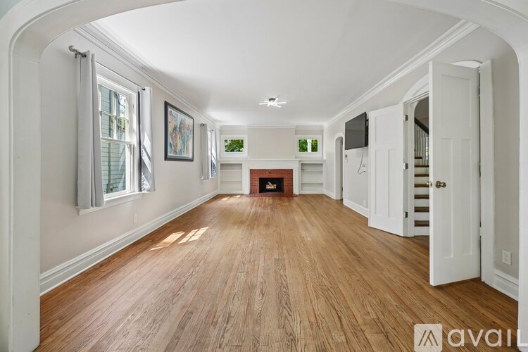 A spacious room with wooden floors and white walls.