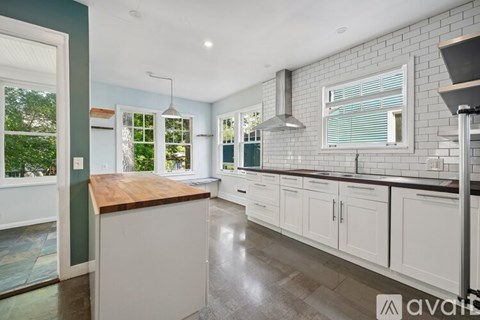 A kitchen with white cabinets and a wooden island.