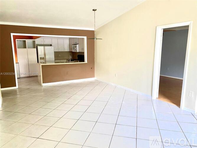 A room with a kitchen visible through the window.