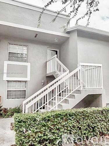 A grey two story house with a white staircase.