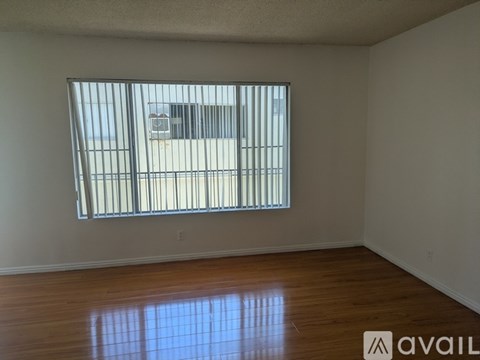 A room with a large window and wooden flooring.
