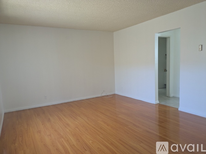 A room with wooden flooring and a door on the right side.