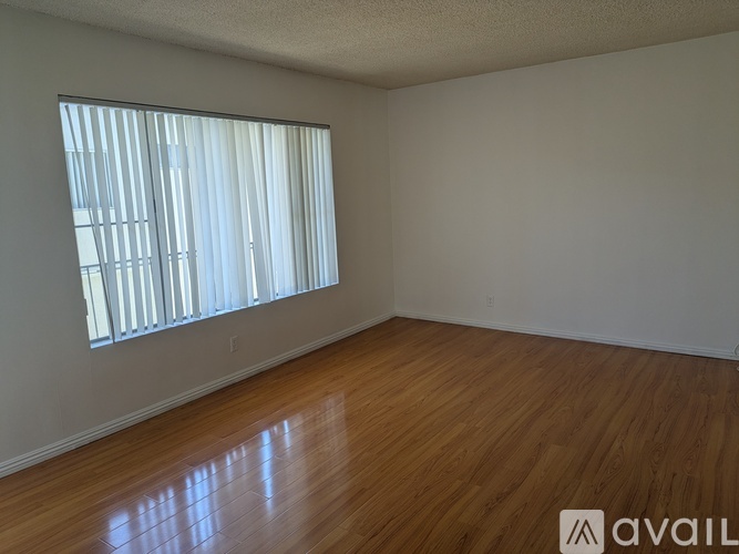A room with wooden flooring and a window with blinds.