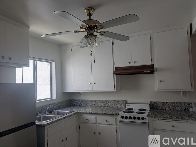 A kitchen with white cabinets and a fan.