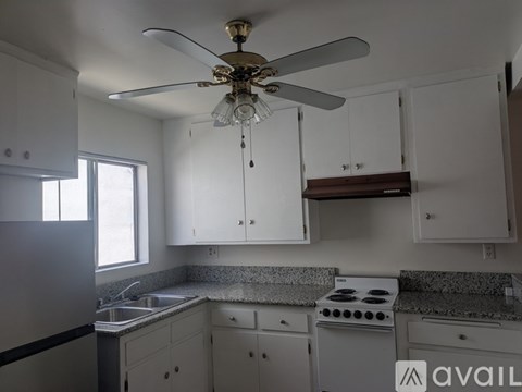 A kitchen with white cabinets and a fan.