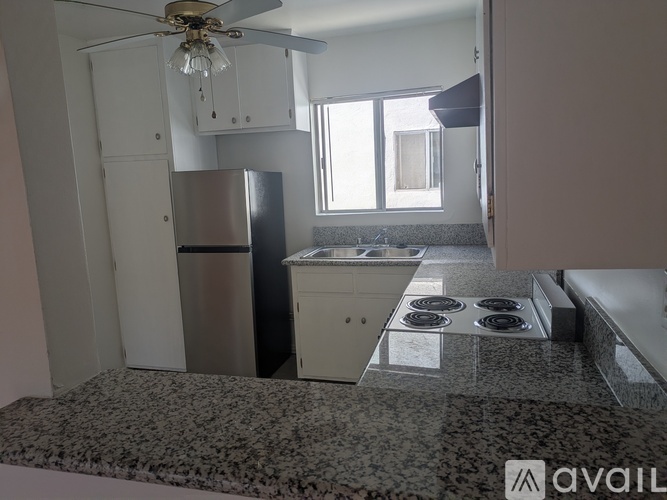 A kitchen with a refrigerator, stove, and a fan.