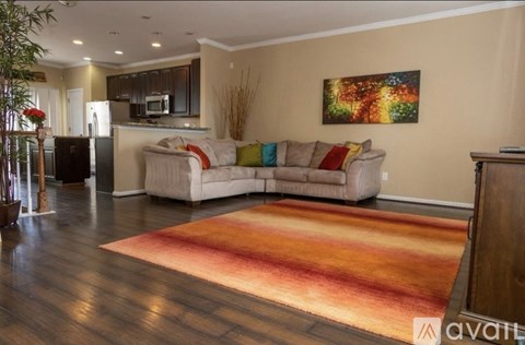 A living room with a couch, a rug, and a painting on the wall.