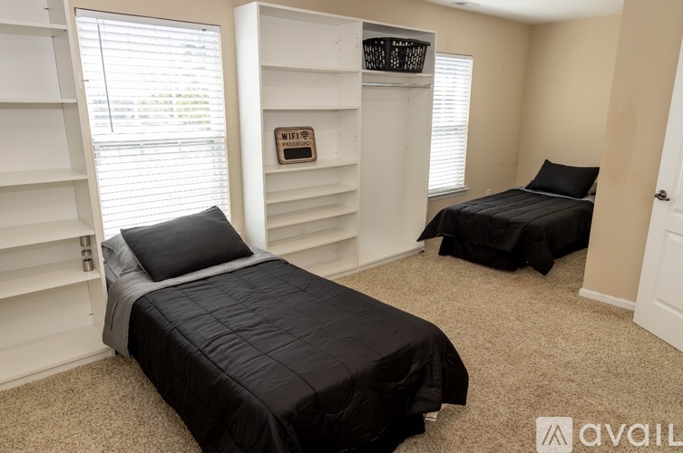 A bedroom with two beds and a shelf unit.