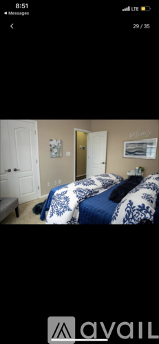 A bedroom with a bed covered in a blue and white comforter.