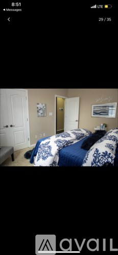 A bedroom with a bed covered in a blue and white comforter.