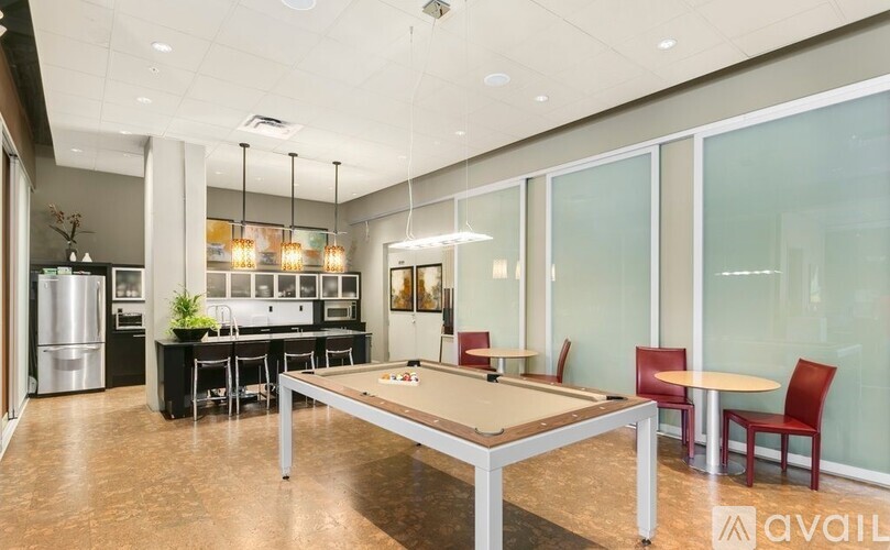 A billiard table is in the middle of a room with a kitchen in the background.