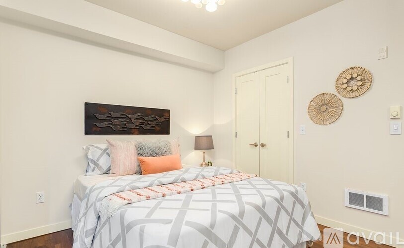 A bedroom with a bed, pillows, a lamp, and a painting on the wall.