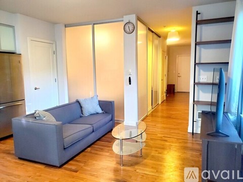 A living room with a grey couch and a glass table.