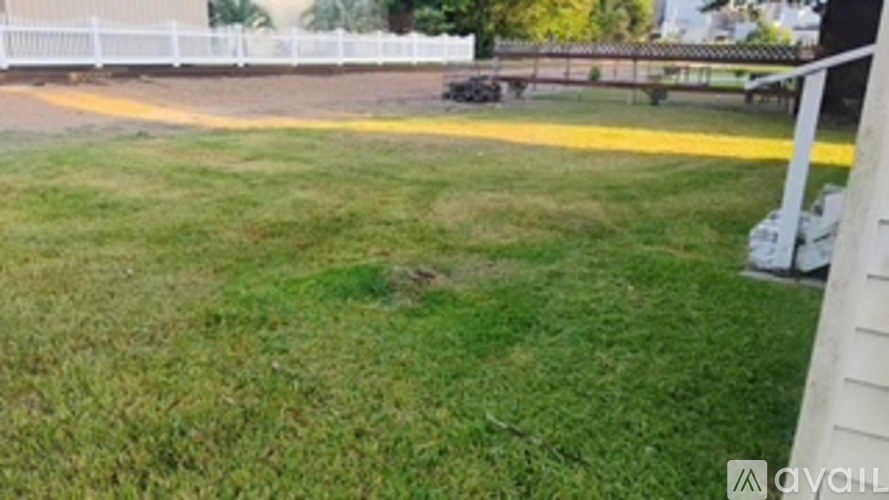 A grassy area with a white fence in the background.