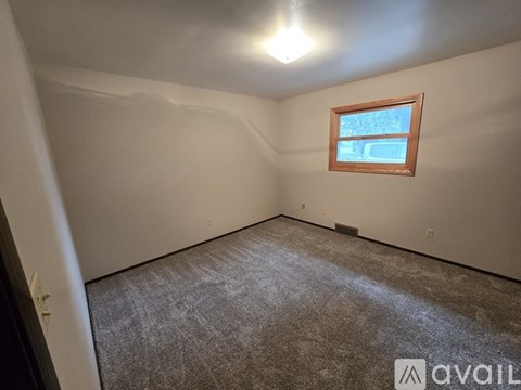 A room with a window and a carpeted floor.