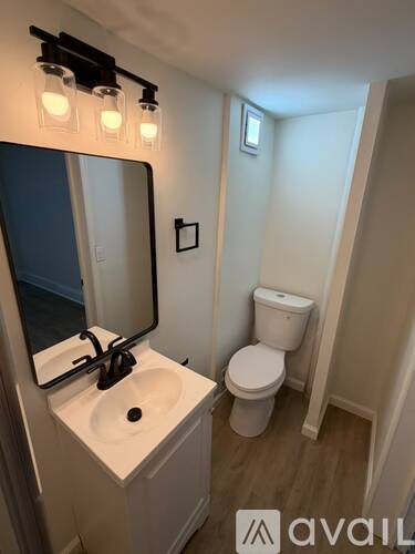 A bathroom with a sink, toilet and mirror.