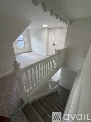 A staircase with a carpeted runner and white balusters leads to a second floor.