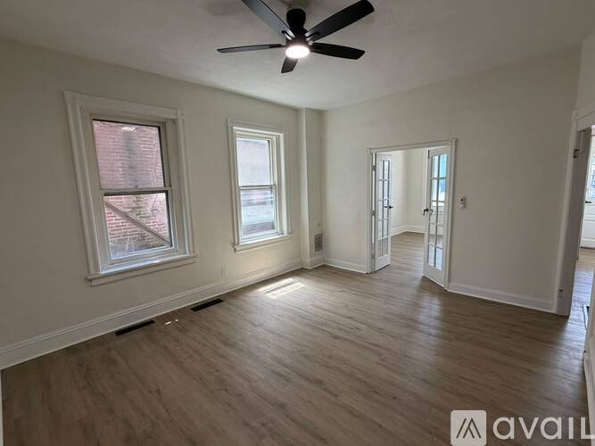 A room with a ceiling fan and wooden flooring.