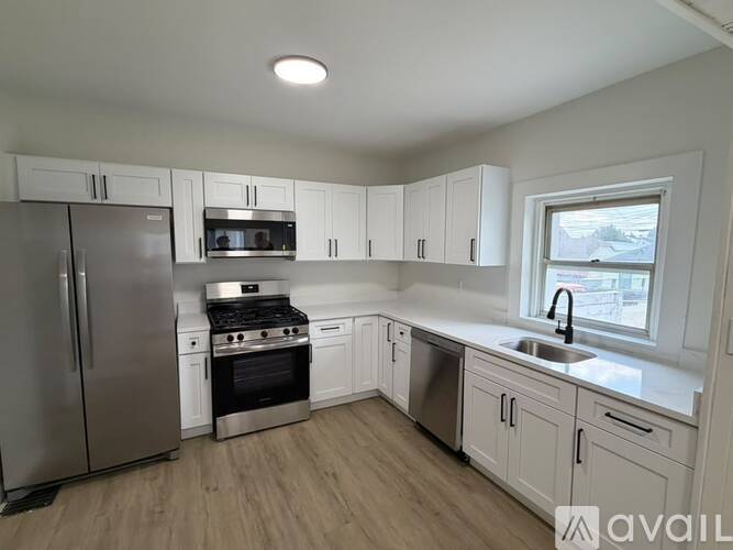 A kitchen with white cabinets and a stainless steel refrigerator.