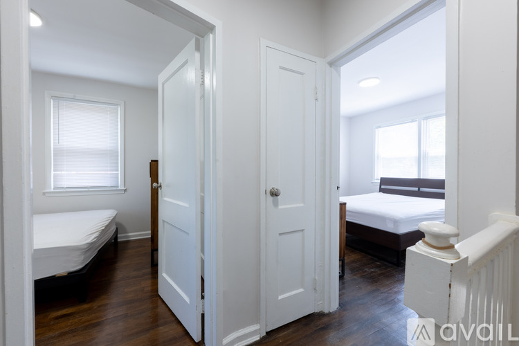 A white bedroom with a bed, dresser, and window.