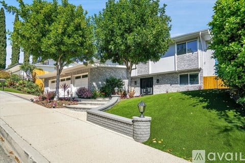 A modern house with a well-maintained lawn and trees.