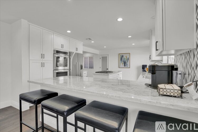 A kitchen with white cabinets and a marble countertop.