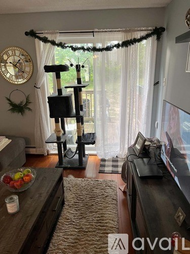A living room with a couch, a clock, a table with a bowl of fruit, and a TV.