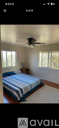 A bedroom with a bed, a ceiling fan, and a window.