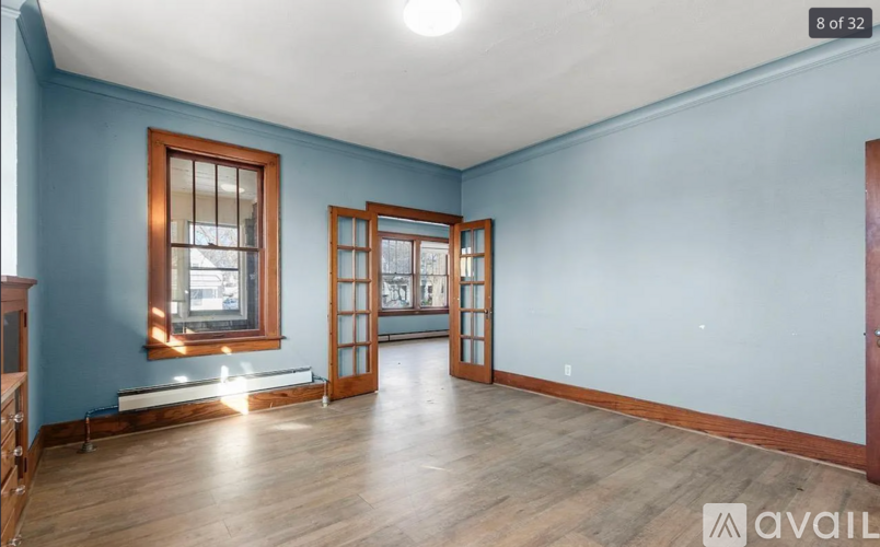 A room with blue walls and wooden floors, featuring a window and a door.