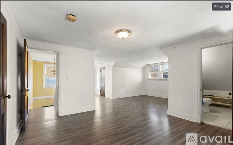 A spacious room with wooden floors and white walls.