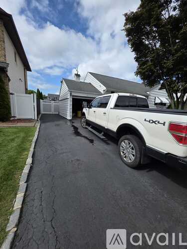 A white Ford truck is parked on a driveway.