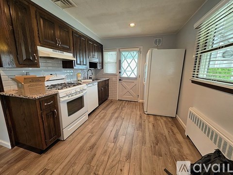 A kitchen with wooden cabinets and a white stove top oven.