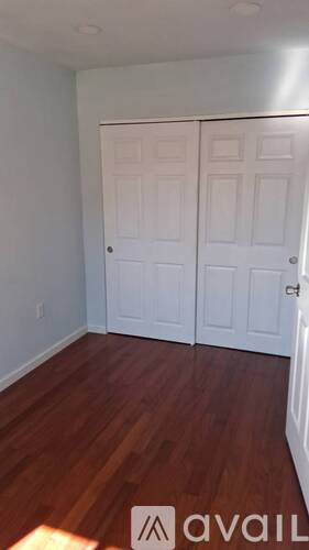 A room with two white doors and wooden floors.