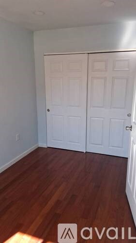 A room with two white doors and wooden floors.