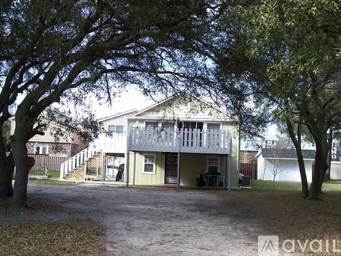 A house with a porch and a tree in front.